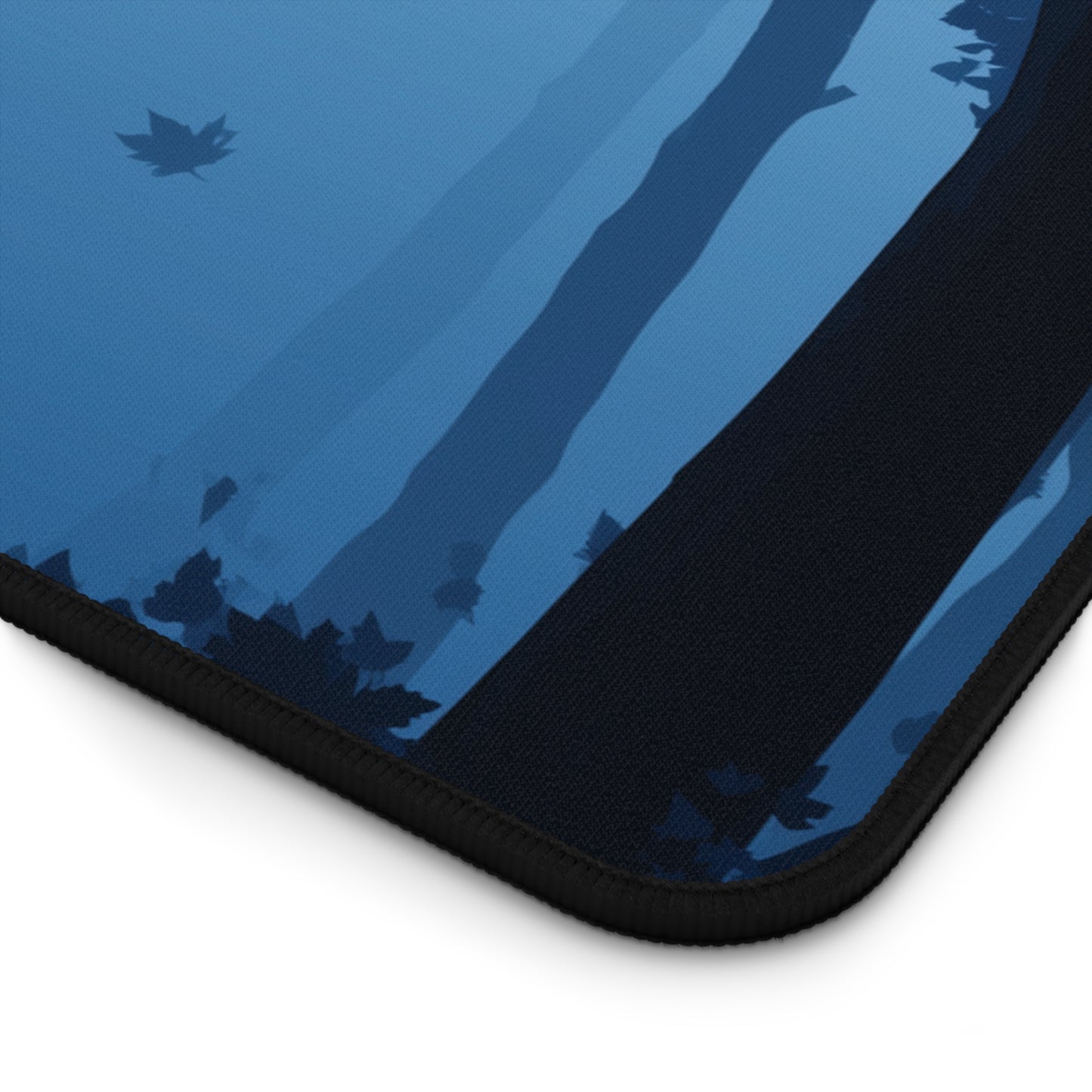 Blue desk mat corner with witch-and-moon artwork and black stitched edge
