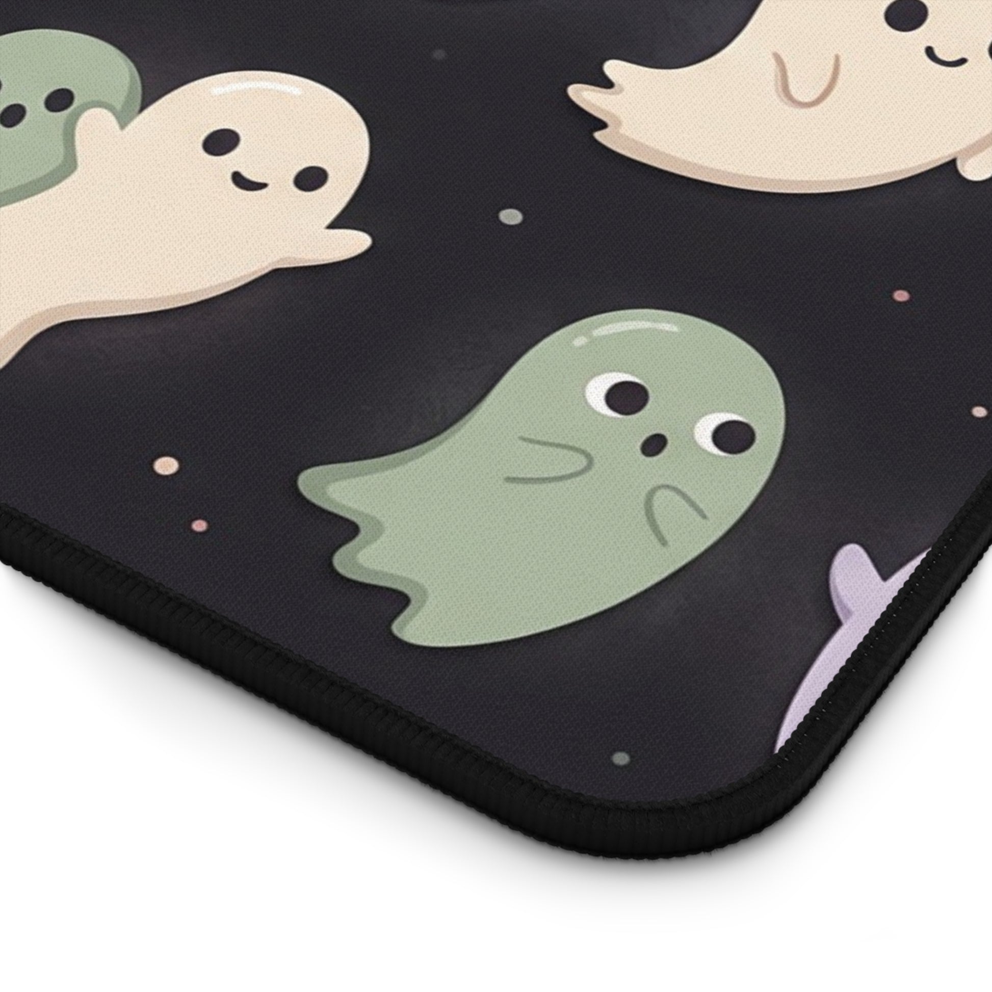 Close-up of pastel ghost pattern desk mat corner with black stitched trim