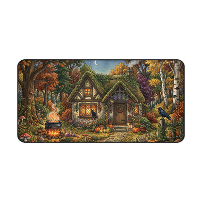 Rounded rectangular desk mat with autumn forest witch cottage scene, pumpkins and glowing cauldron