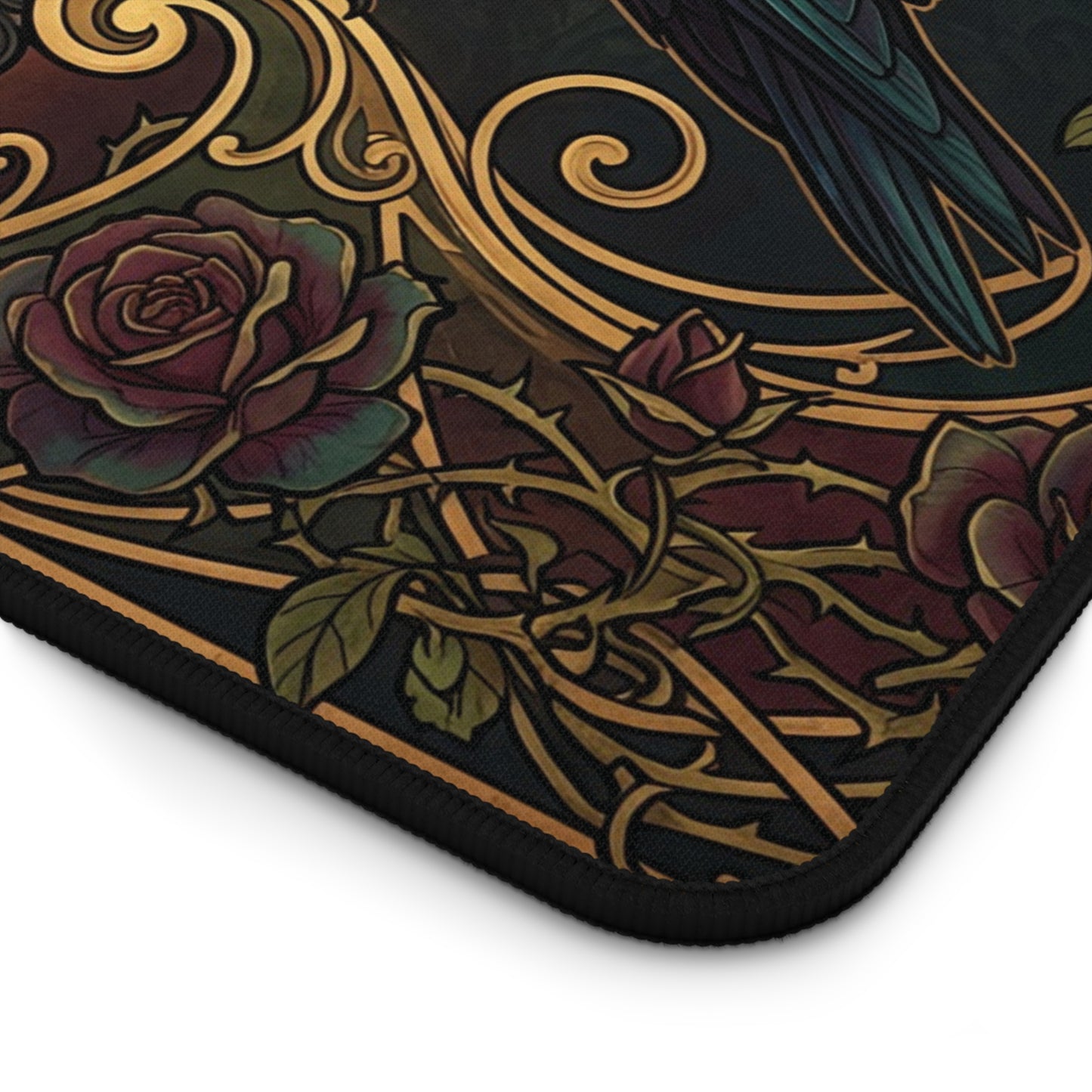 Close-up of a decorative mouse pad showing a dark background with an Art Nouveau-style design featuring roses, thorns, swirling gold lines, and a bird in teal and black.