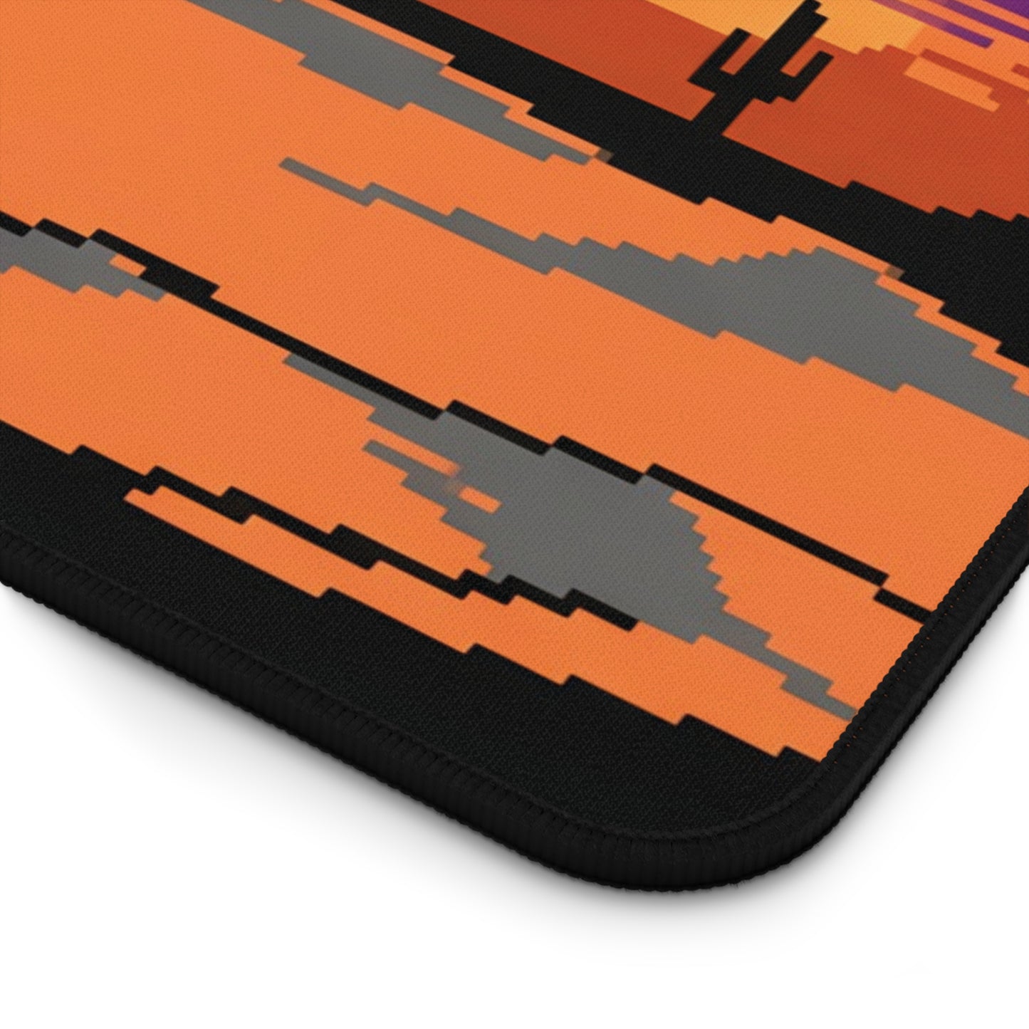 Pixel art desk mat close-up with black stitched edge and orange desert pixel pattern