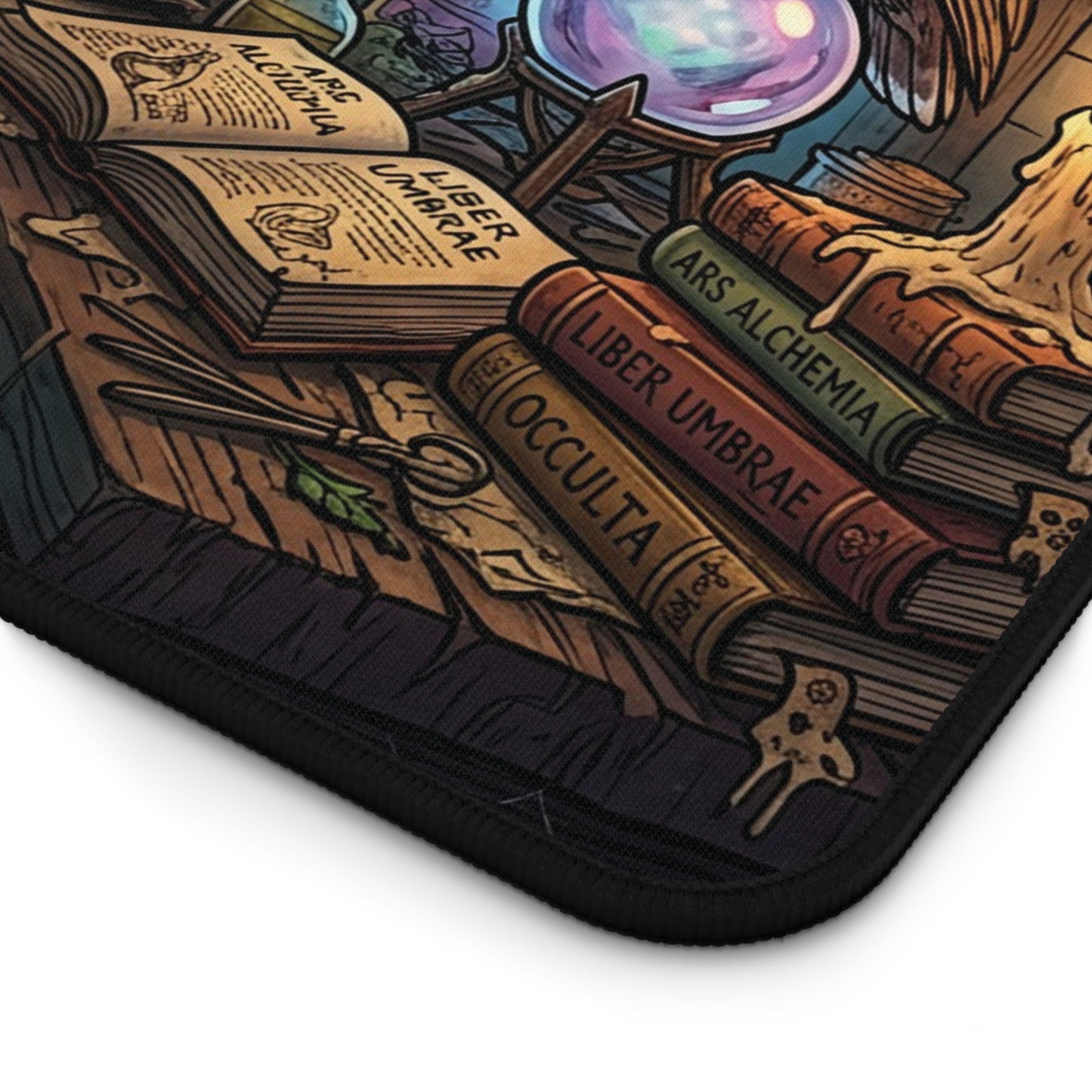 A close-up of a black-edged mouse pad featuring a detailed fantasy illustration of occult books, a crystal ball, and magical tools on a wooden surface.