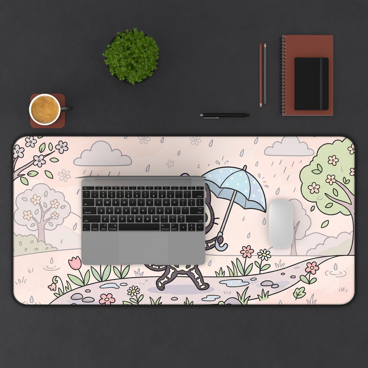 Skeleton cat desk mat under a laptop keyboard, pastel rain-and-flowers design with dark edge