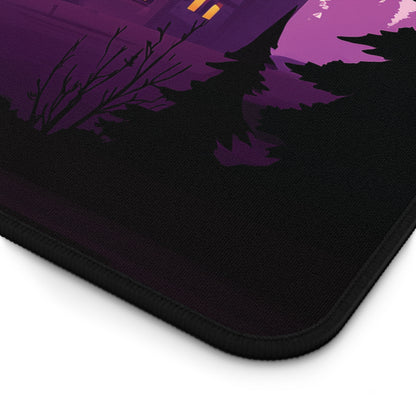 A close-up of a black mouse pad with a purple and magenta graphic of a spooky haunted house and trees, shown on a white background.