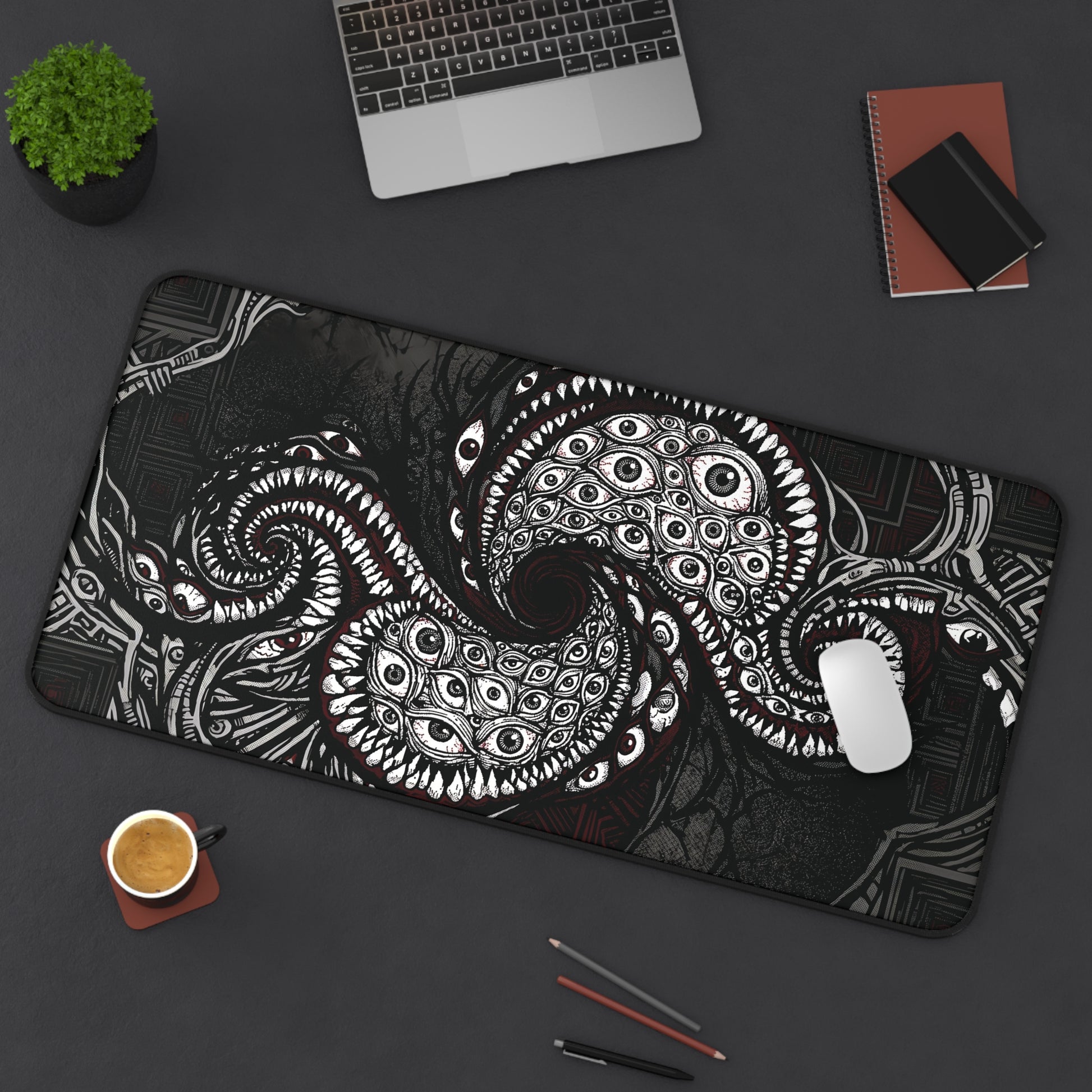 Black desk mat with white and red cosmic tentacle eye design, stitched edge
