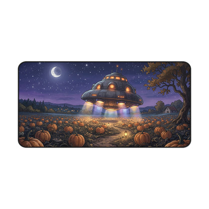 A rectangular desk mat with rounded corners featuring a colorful cartoon illustration of a glowing UFO flying over a pumpkin patch at night under a starry sky and crescent moon.
