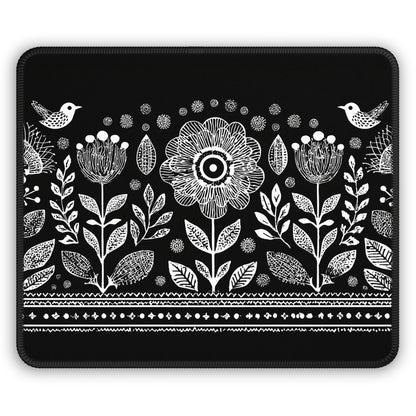 A rectangular black mouse pad with rounded corners, featuring a white hand-drawn style botanical pattern of flowers, leaves, birds, and decorative borders.